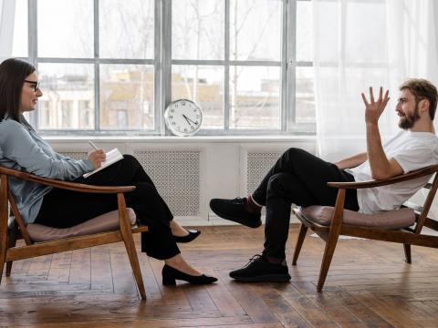 Das Bild zeigt einen Mann und eine Frau, die sich im Sprechzimmer gegenüber sitzen. 